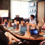 A group of people collaborating around a table, each using laptops to work on a proposal tool.