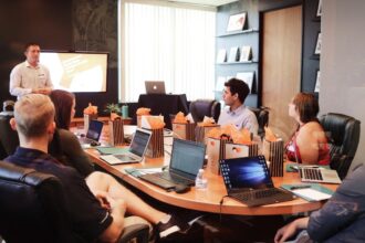 A group of people collaborating around a table, each using laptops to work on a proposal tool.