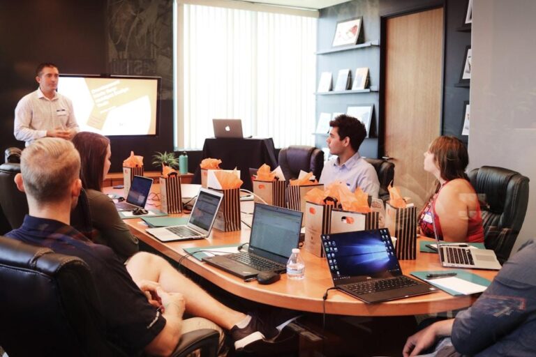 A group of people collaborating around a table, each using laptops to work on a proposal tool.
